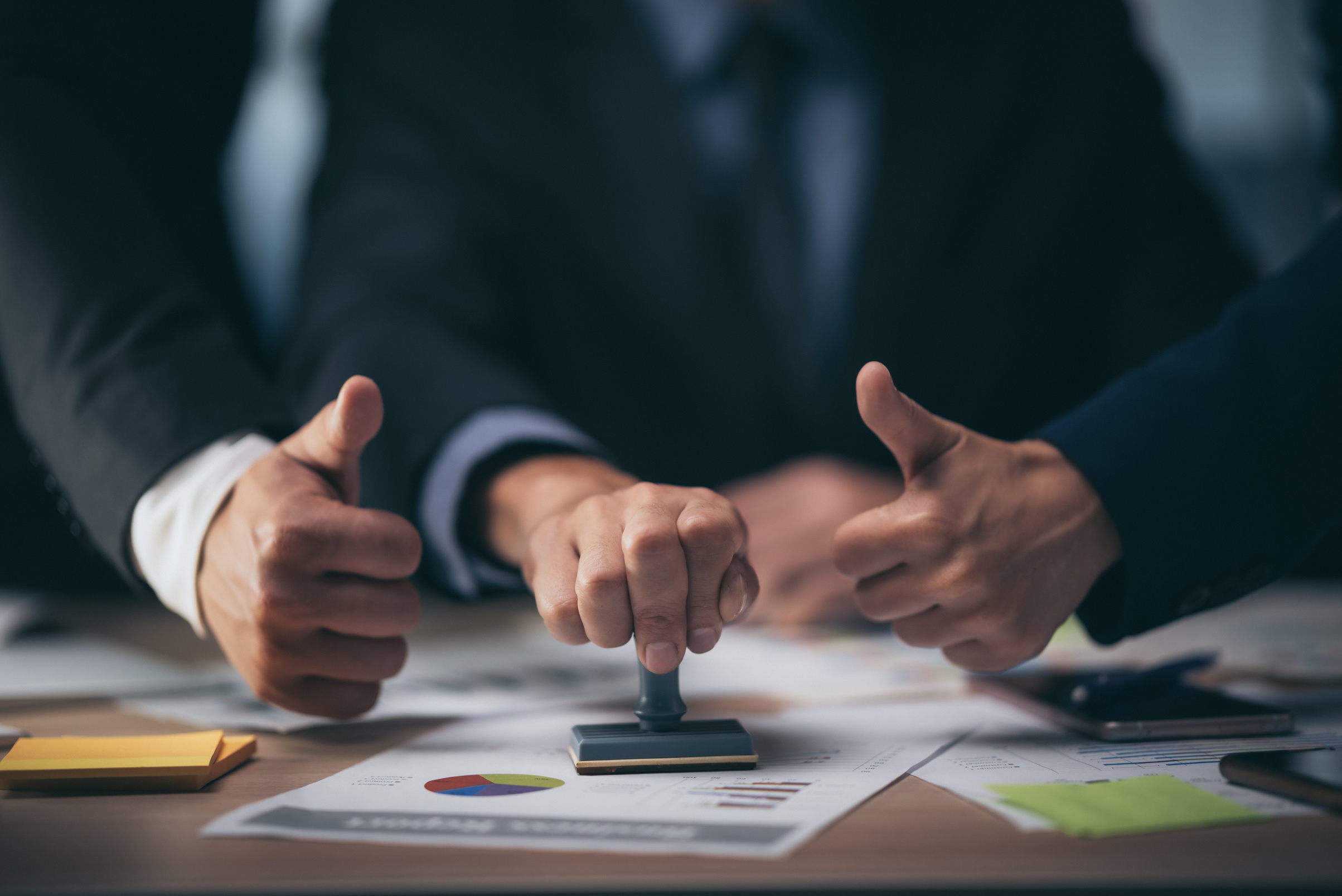 Businessmen Stamping Document and Giving Thumbs Up